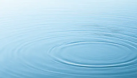 Surface d'eau bleue avec des ondes circulaires, créant une ambiance apaisante et relaxante, idéale pour un fond de spa et de massages.