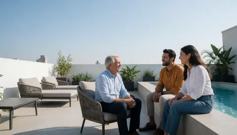 Trois personnes discutent joyeusement sur une terrasse d'hôtel avec piscine, meubles modernes et vue panoramique sur la ville.