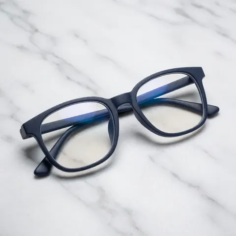 Paire de lunettes de lecture avec une monture bleue posée sur une surface en marbre, éclairage doux et propre.