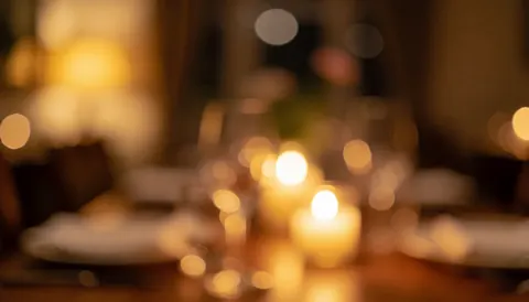 Ambiance chaleureuse de restaurant avec des tables éclairées par des bougies et des lumières douces, idéale pour superposer du texte.