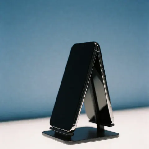 Un téléphone intelligent noir posé sur un support noir, présenté sur un fond bleu dégradé, idéal pour la publicité technologique et la promotion de produits électroniques.