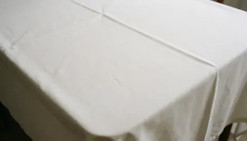 Table recouverte d'une nappe blanche, idéale pour les mariages et les événements, surface propre et élégante pour les textes.