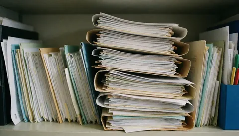 Des dossiers et des classeurs empilés sur une étagère de bureau, offrant un espace pour le texte, idéal pour les thèmes commerciaux et les accords.