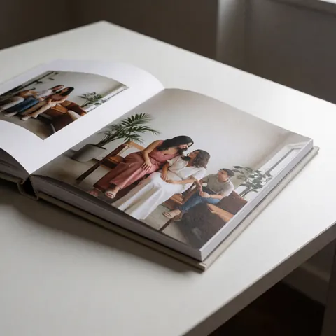 Album photographique ouvert posé sur une surface blanche, révélant des images intérieures avec du papier de qualité et un éclairage doux.