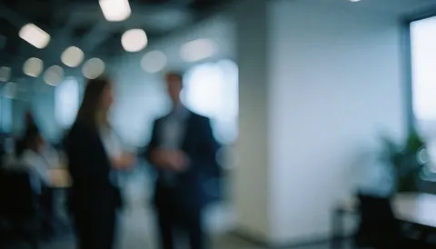 Fond d'entreprise avec personnes floues, lumières de bureau et espace pour texte, tons froids et profonds.