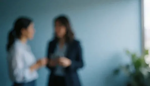 Fond de bureau avec deux personnes en conversation, tons bleus et espace libre à droite, idéal pour textes financiers.