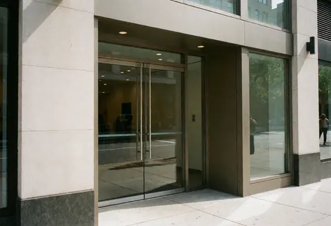 Façade moderne d'un commerce avec des portes en verre reflétant la rue, idéale pour les entreprises de climatisation.