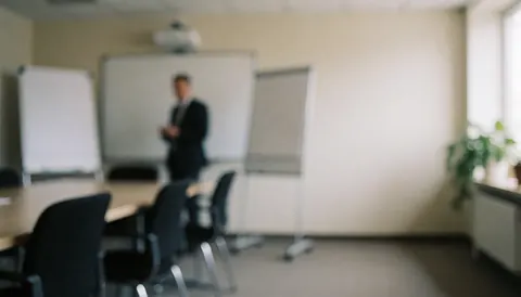Salle de réunion équipée de tableaux blancs, de chaises noires et d'une personne debout en arrière-plan, idéale pour des présentations.
