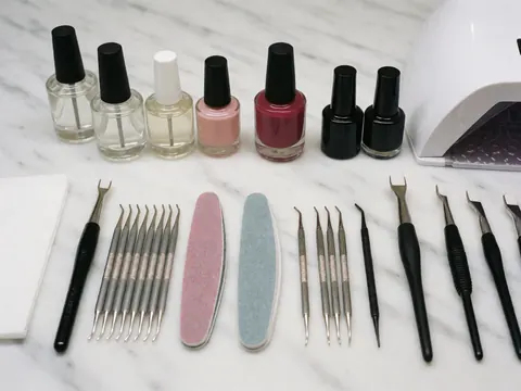 Ensemble d'outils de manicure et vernis à ongles organisés sur une surface en marbre blanc, idéal pour les salons de beauté.