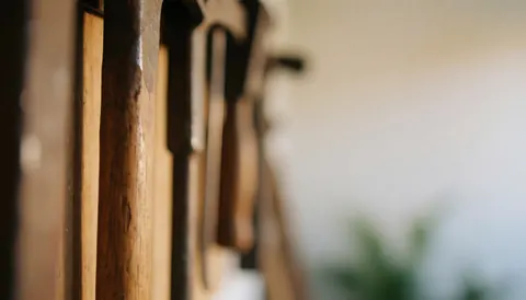 Outils en métal et en bois accrochés dans un garage, avec un arrière-plan flou et chaleureux adapté aux textes commerciaux.