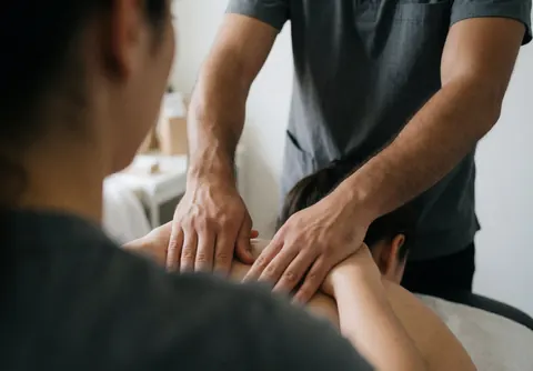 Un homme effectue un massage facial sur une femme dans un salon d'esthétique avec des gestes professionnels.