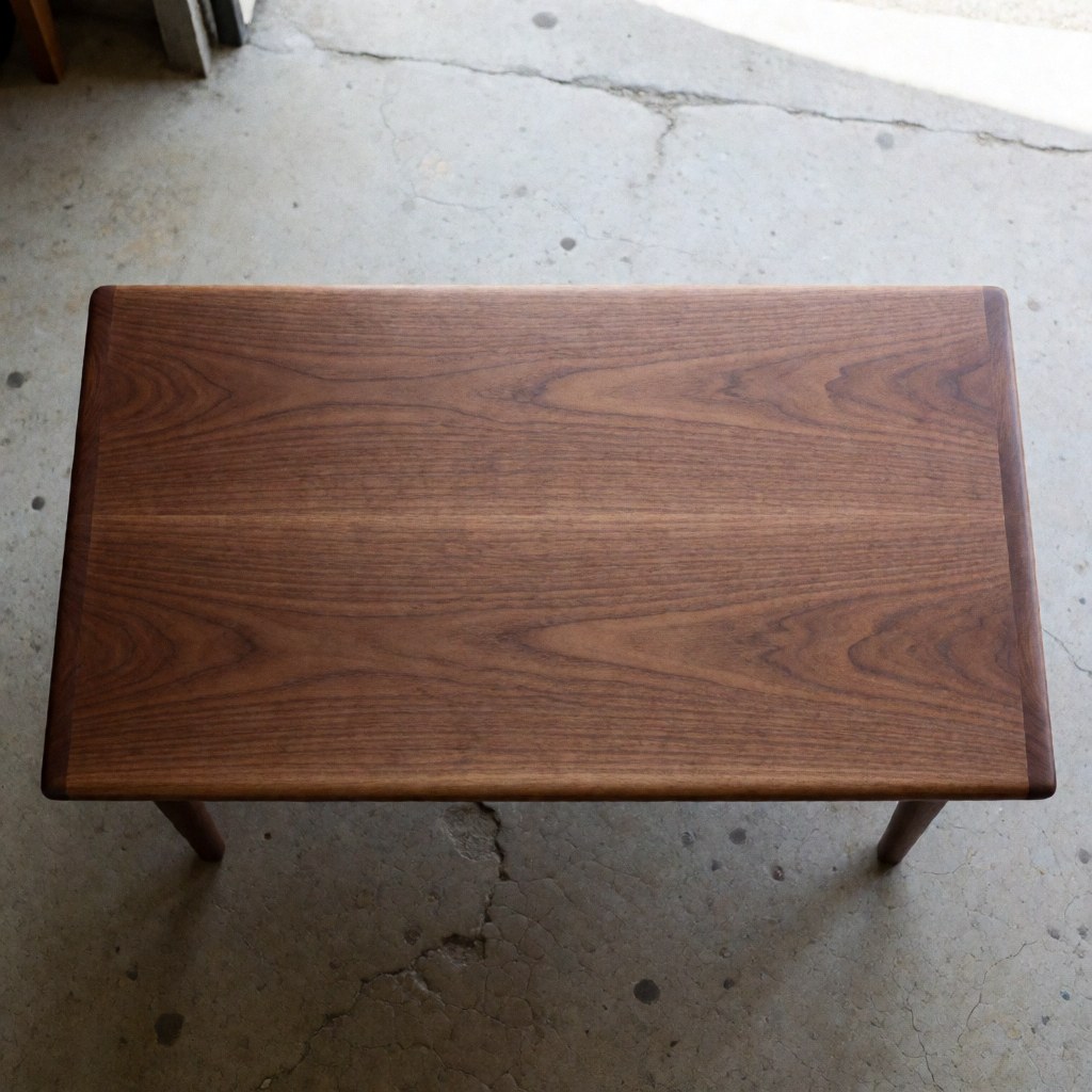 Vue d'une table en bois massif à la surface polie reposant sur un sol en béton fissuré, mettant en valeur la texture naturelle du matériau.