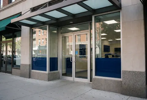 Façade d'un établissement de sécurité doté de portes en verre renforcé, d'un auvent moderne et de murs en pierre, adapté aux services professionnels.