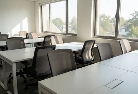 Bureau moderne vide équipé de tables blanches et de chaises de bureau prêtes pour des réunions ou le télétravail.