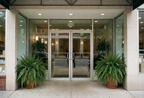 Façade d'un établissement de soins avec des portes en verre, des plantes vertes en pot et une ambiance professionnelle.