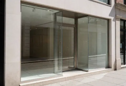 Façade d'un bâtiment contemporain avec de grandes baies vitrées et une porte d'entrée, sans personnes ni meubles visibles.