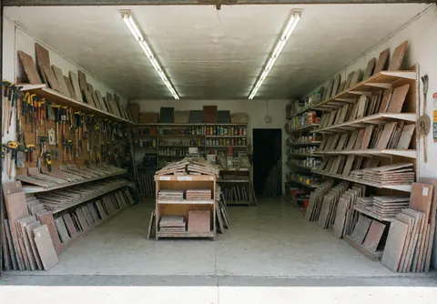 Intérieur d'un entrepôt rempli d'étagères chargées de planches, d'outils et de produits de bricolage pour la rénovation.