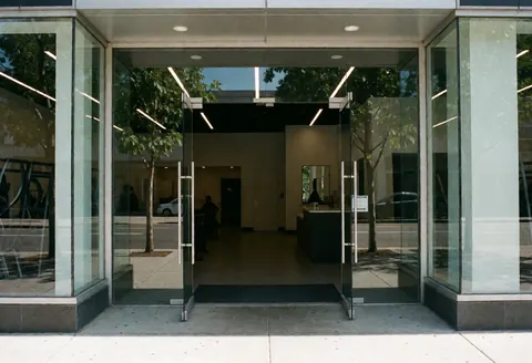 Façade d'un bâtiment contemporain présentant une entrée vitrée et un intérieur avec un comptoir de réception.