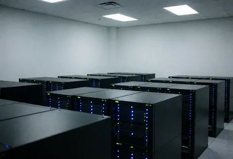 Salle de serveurs propre et moderne avec des rangées d'équipements informatiques affichant des lumières bleues actives.