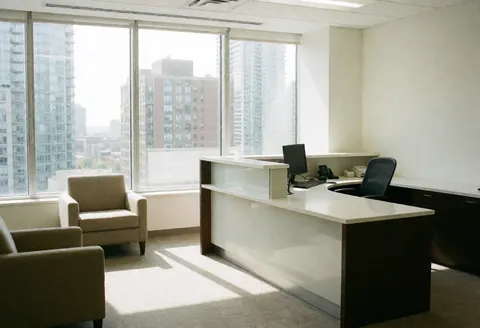 Réception moderne avec un comptoir blanc, des chaises et une vue panoramique sur des gratte-ciel dans un bureau en ville.