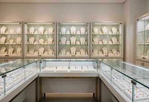 Vitrines élégantes exposant des colliers et des bagues dans une boutique de bijoux moderne et luxueuse.