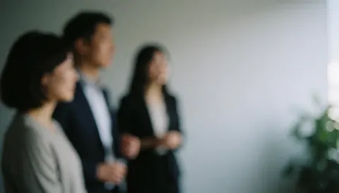 Trois personnes d'affaires debout lors d'une réunion de bureau, en train de discuter avec un fond flou.