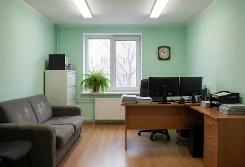 Espace de travail professionnel équipé de plusieurs ordinateurs, d'un canapé confortable et d'une fenêtre laissant entrer la lumière naturelle.