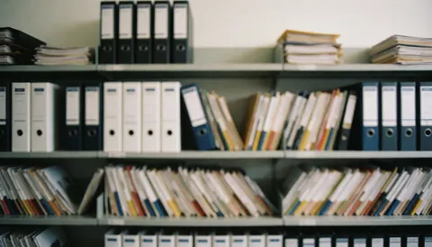 Des étagères remplies de dossiers et documents dans un bureau comptable, avec un fond flou adapté pour ajouter du texte professionnel.