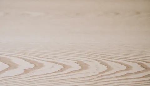 Surface en bois clair présentant des motifs naturels et une texture douce, idéale pour servir de fond professionnel dans divers projets visuels.