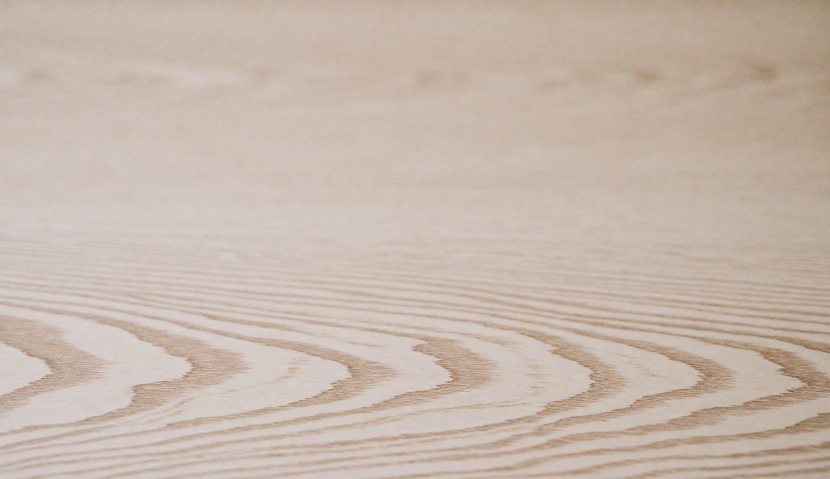 Surface en bois clair présentant des motifs naturels et une texture douce, idéale pour servir de fond professionnel dans divers projets visuels.
