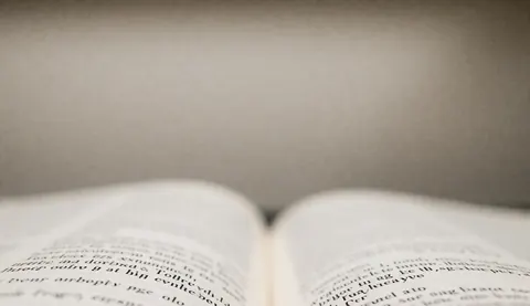 Page de livre ouverte montrant du texte flou, servant de fond pour la lecture, l'étude ou le contenu éducatif dans un contexte professionnel.