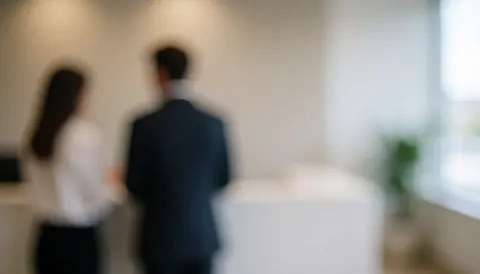Fond flou d'une réception de bureau avec deux personnes de dos, murs clairs et espace pour texte au centre et à droite.