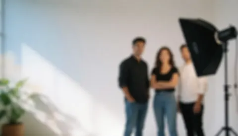Trois adultes professionnels posant debout devant un fond blanc lumineux éclairé par des lumières de studio.
