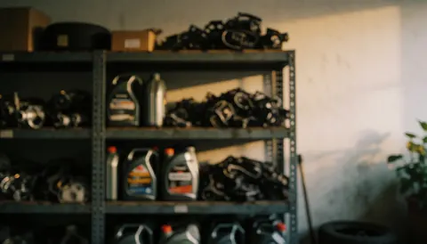 Étagères remplies d'huiles et de pièces mécaniques dans un garage automobile, servant de fond texturé pour vos projets.