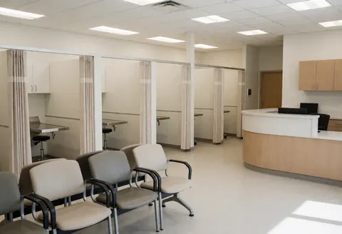 Vue intérieure propre d'une clinique vétérinaire avec salles d'examen, fauteuils d'attente et comptoir de réception prêts à accueillir patients et propriétaires.