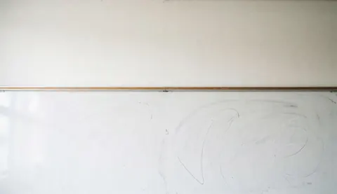 Fond de tableau blanc avec des marques de craie, idéal pour du texte éducatif, sans personnes ni objets, éclairage lumineux et propre.