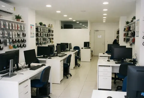 Vue intérieure d'un espace de travail de support informatique avec bureaux, écrans, chaises et étagères de câbles organisés.