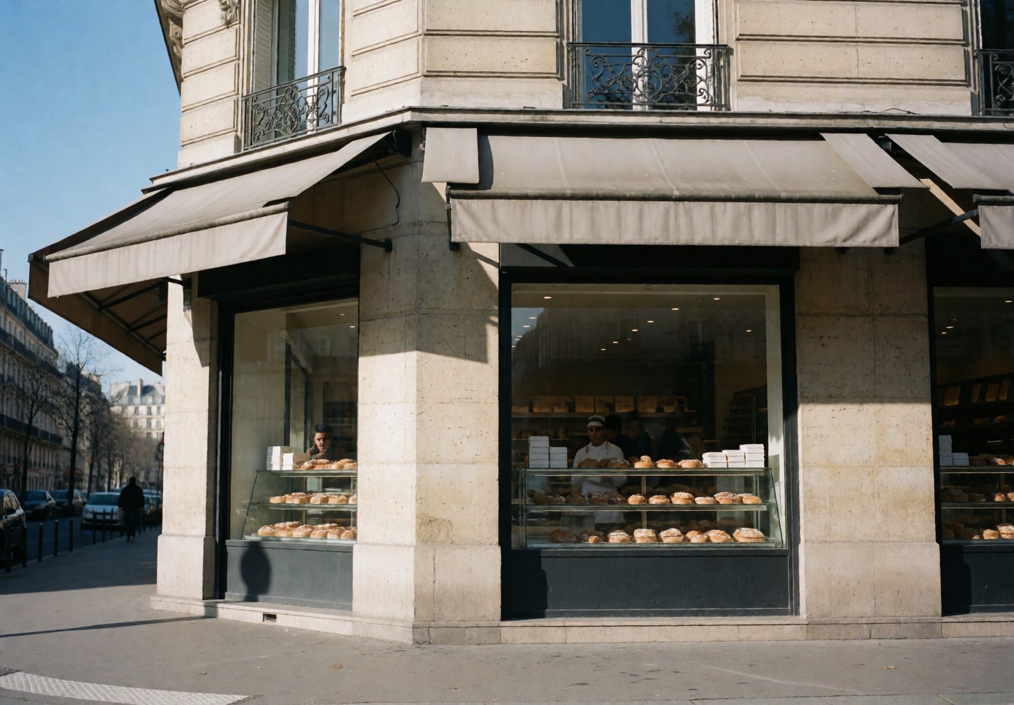 Vitrine de pâtisserie exposant des gâteaux et des pains, avec des boulangers servant des clients dans un magasin.