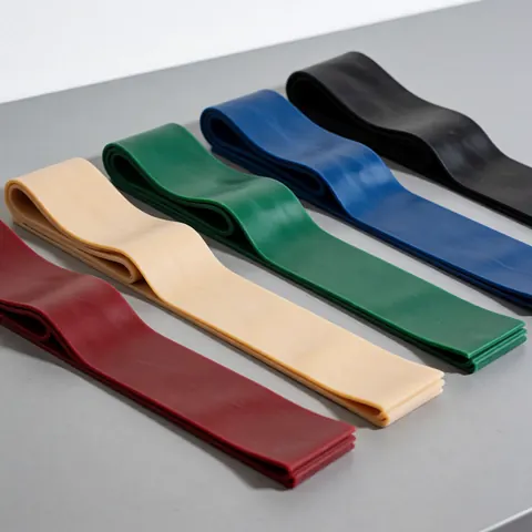 Cinq bandes élastiques de couleurs différentes rouge beige vert bleu et noir alignées en diagonale sur un fond gris uni pour le fitness