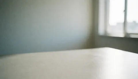Un bureau blanc lisse dans un bureau avec un mur et une fenêtre en arrière-plan, idéal pour les présentations ou le travail.