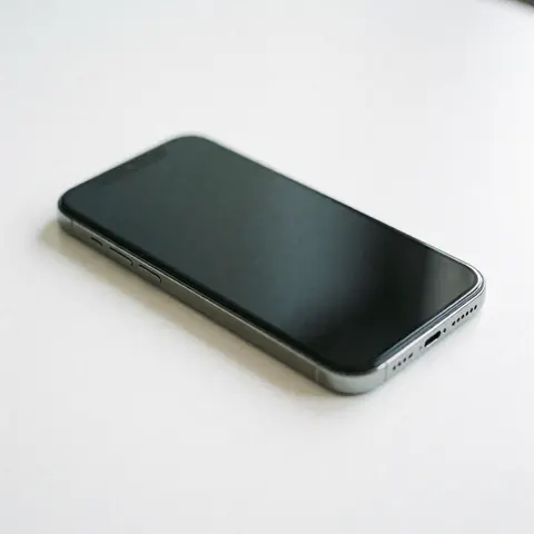 Un téléphone portable moderne de couleur grise posé sur une surface blanche lisse et propre, mettant en valeur son design élégant.