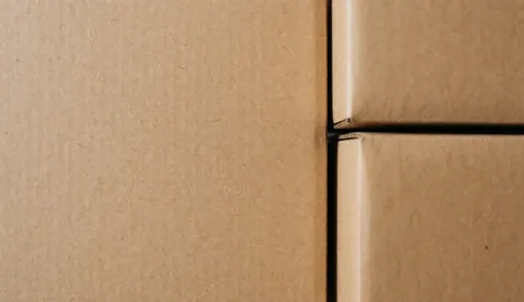 Empilement de cartons marron prêts à être emballés et envoyés aux clients, vue rapprochée sur fond neutre.