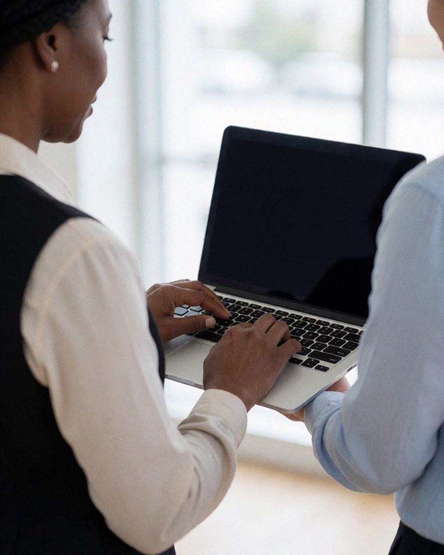 Un homme et une femme travaillent ensemble sur un ordinateur portable dans un bureau moderne baigné de lumière naturelle.