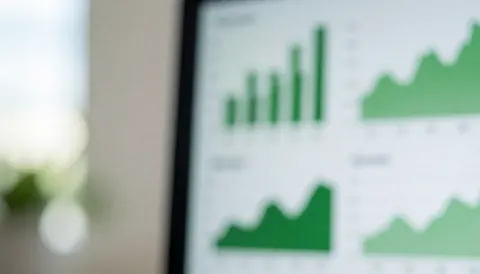 Écran affichant des graphiques à barres et en lignes verts montrant des données financières dans un bureau moderne.