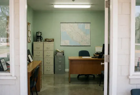 Vue d'un bureau équipé d'un bureau, de classeurs, d'une carte au mur, d'un ordinateur