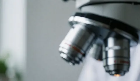 Gros plan sur les lentilles d'un microscope dans un laboratoire clinique avec un fond flou.