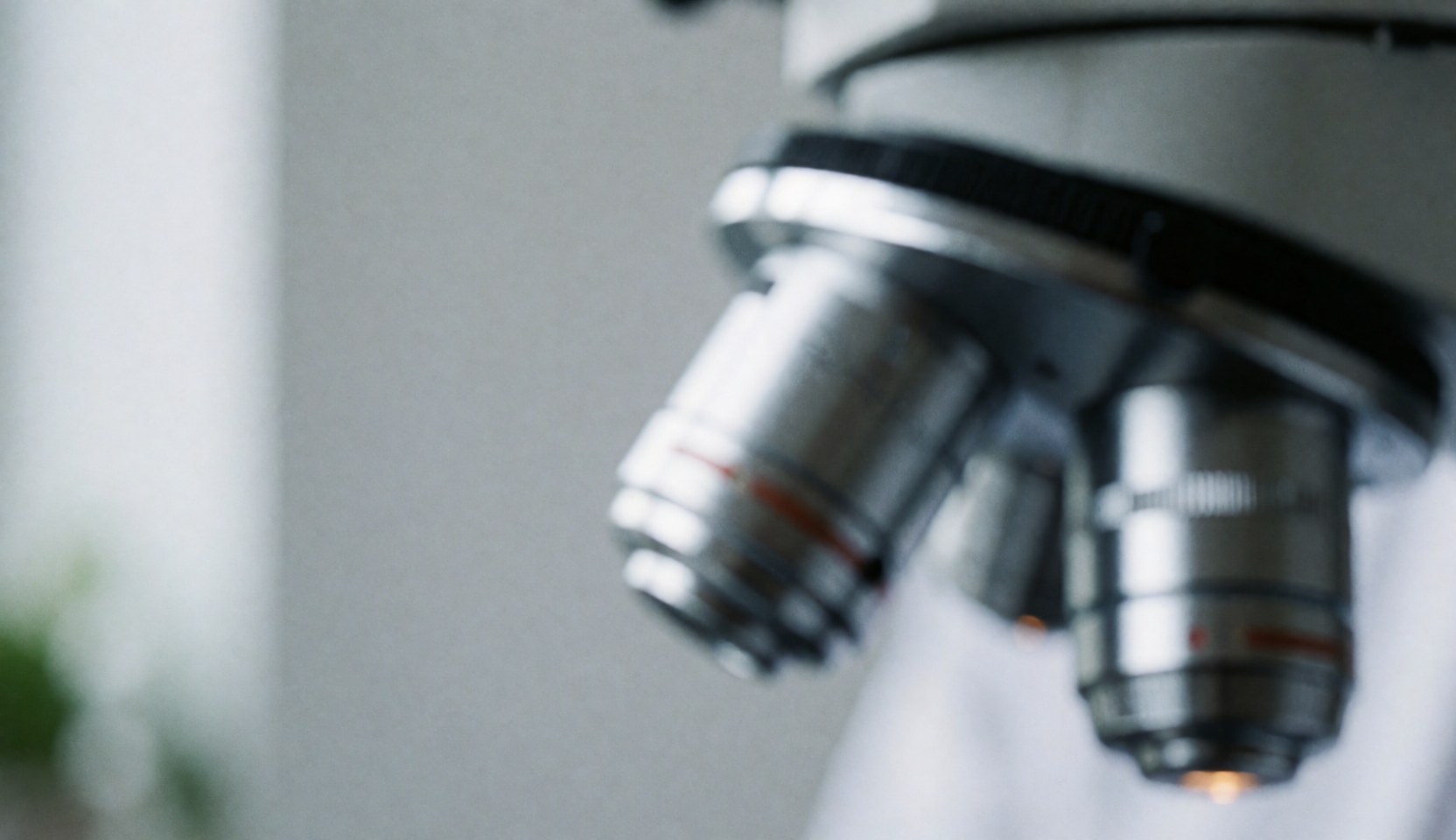Gros plan sur les lentilles d'un microscope dans un laboratoire clinique avec un fond flou.