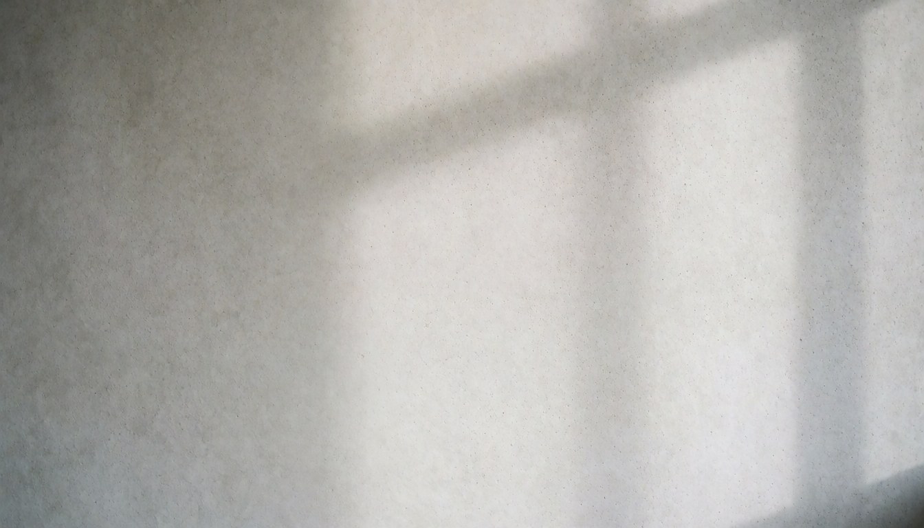 Mur en béton texturé éclairé par la lumière naturelle créant des ombres douces dans un intérieur minimaliste.