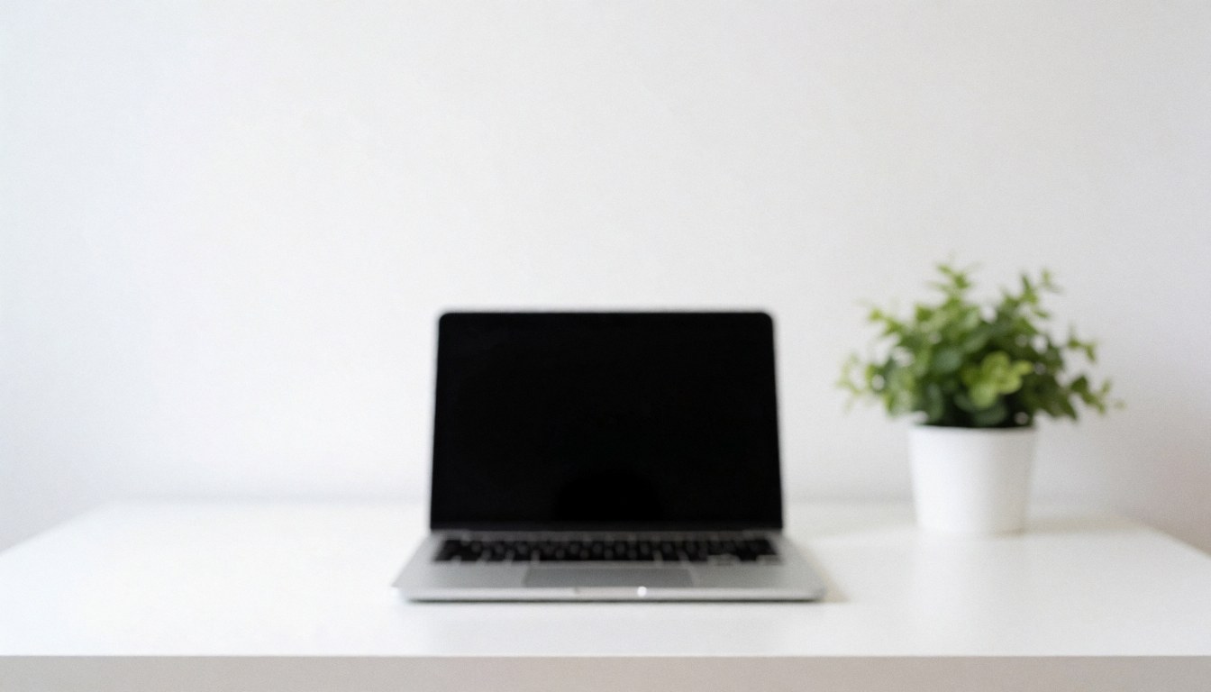 Un ordinateur portable posé sur un bureau blanc accompagné d'une petite plante dans un pot blanc à côté.