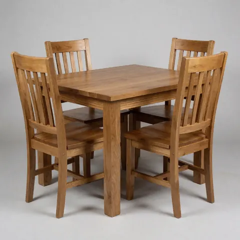 Une table à manger rectangulaire en bois massif accompagnée de quatre chaises assorties sur un fond gris clair uni.